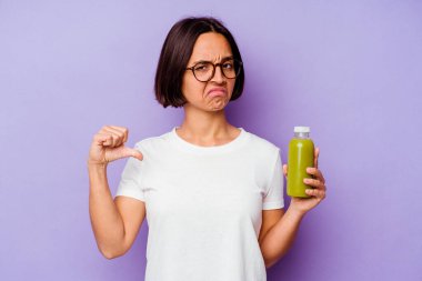 Mor arka planda izole edilmiş sağlıklı bir smoothie tutan genç melez kadın hoşlanmadığı bir hareket sergiliyor. Anlaşmazlık konsepti.