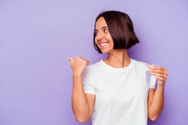 Mor arka plan noktalarında bir bardak su tutan genç melez bir ırk parmak uzakta, gülüyor ve kaygısız..