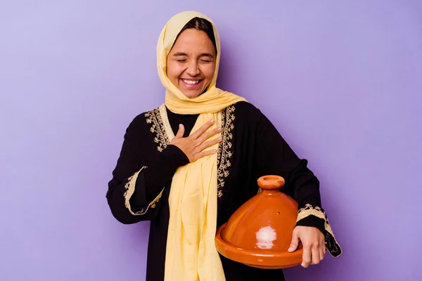 若いですモロッコ女性保持していますAタジン隔離された上に紫の背景笑アウト大声で手に胸 — ストック写真