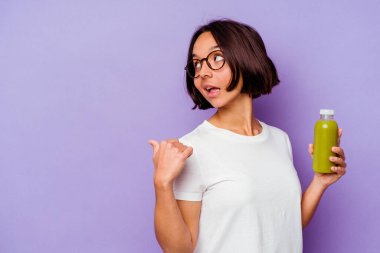 Genç melez kadın elinde sağlıklı bir meyve püresi tutuyor. Mor arka planda izole edilmiş, baş parmak uzakta, gülen ve kaygısız..