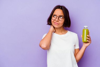 Mor arka planda izole edilmiş sağlıklı bir smoothie tutan genç bir ırk kadını başının arkasına dokunuyor, düşünüyor ve bir seçim yapıyor..