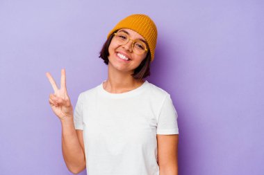 Mor arka planda yünlü şapka takan genç bir ırk kadını iki numarayı parmaklarıyla gösteriyor..