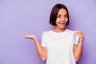 Mor arka planda bir bardak su tutan genç melez bir ırk bir palmiye üzerinde fotokopi alanı ve belinde bir el daha olduğunu gösteriyor..