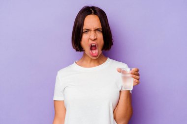 Mor arka planda izole edilmiş bir bardak su tutan genç bir ırk çok kızgın ve agresif çığlıklar atıyor..