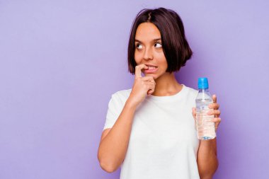 Mor arka planda izole edilmiş su şişesi tutan genç melez bir ırk. Bir şeyin fotokopi alanına baktığını düşünerek rahatlamış..