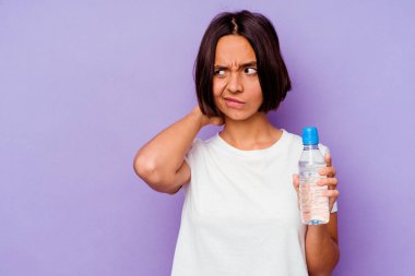 Mor arka planda izole edilmiş su şişesini tutan genç melez ırk kafasının arkasına dokunuyor, düşünüyor ve bir seçim yapıyor..