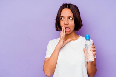 Mor arka planda izole edilmiş su şişesini tutan genç melez ırk gizli bir sıcak fren haberinin olduğunu söylüyor.