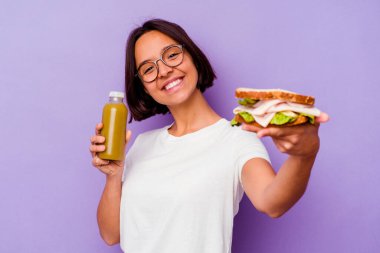 Mor arka planda sağlıklı bir smoothie ve sandviç tutan genç bir ırk kadını.