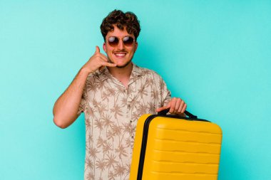 Mavi arka planda sarı bir bavul tutan genç bir gezgin parmakları olan bir cep telefonu hareketi gösteriyor..