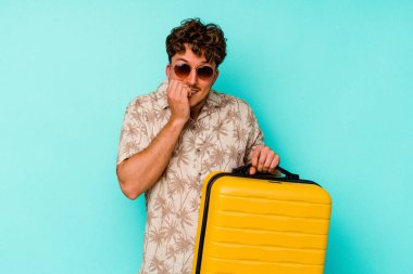 Mavi arka planda sarı bir bavul taşıyan genç bir gezgin tırnaklarını yiyor, gergin ve çok endişeli..