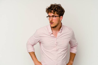 Beyaz arka planda izole edilmiş genç beyaz adam gülümseyen, neşeli ve keyifli bir tarafa bakıyor..