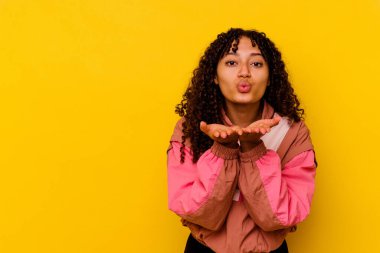 Genç melez kadın pembe arka planda izole edilmiş dudaklar kıvrılmış ve hava öpücüğü göndermek için avuç içleri tutulmuş..