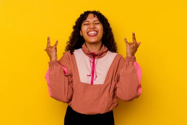 Pembe arka planda izole edilmiş genç melez kadın parmaklarıyla taş hareketi gösteriyor.