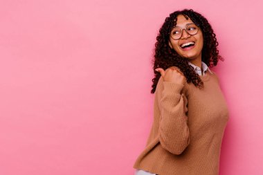 Pembe arka planda izole edilmiş genç melez bir kadın başparmak uzakta, gülüyor ve kaygısız..