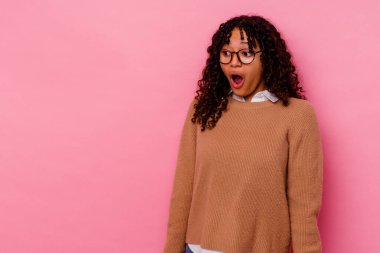 Pembe arka planda soyutlanmış genç melez bir kadın gördüğü bir şey yüzünden şoka uğruyor..