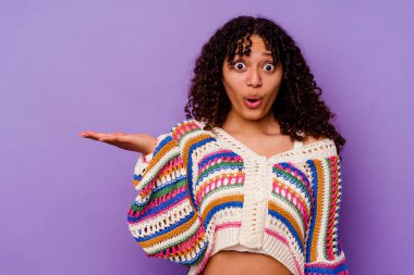 Mor arka planda izole edilmiş genç melez kadın avuç içlerindeki kopya alanını tutmaktan etkilenmiş..