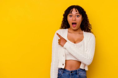 Sarı arka planda izole edilmiş genç, melez bir kadın.