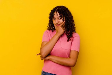 Genç melez kadın sarı arka planda izole edilmiş. Bir strateji planlıyor, bir iş yolu düşünüyor..