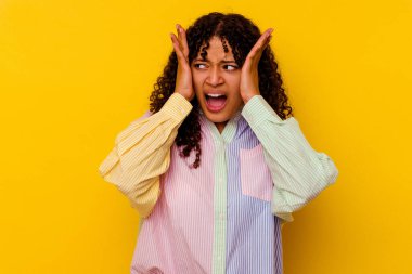 Sarı arka planda izole edilmiş genç bir ırk kadını. Kulaklarını ellerle kapatıyor. Çok yüksek ses duymamaya çalışıyor..