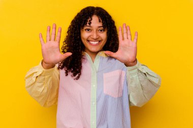 Sarı arka planda izole edilmiş genç melez kadın on numarayı elleriyle gösteriyor..