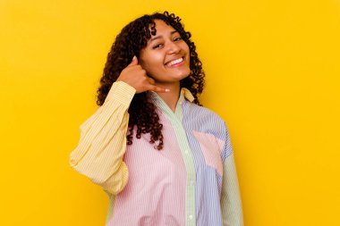 Sarı arka planda izole edilmiş genç melez bir kadın parmakları olan bir cep telefonu hareketi gösteriyor..