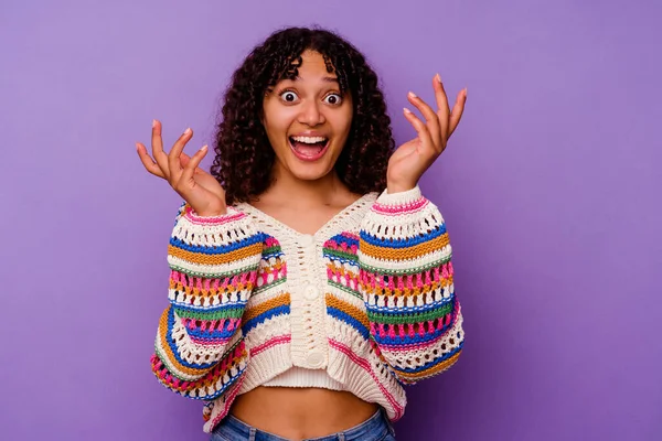 Mor arka planda izole edilmiş genç melez kadın hoş bir sürpriz yaşıyor, heyecanlı ve el kaldırıyor..