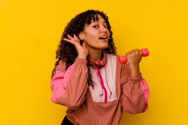 Sarı arka planda soyutlanmış genç, melez bir kadın.