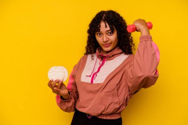 Sarı arka planda izole edilmiş pirinç keki yiyen genç bir ırk sporcusu.