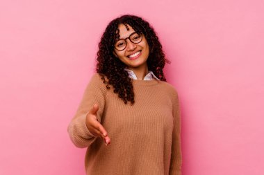 Pembe arka planda soyutlanmış genç melez bir kadın selamlaşma jesti olarak kameraya uzanıyor..