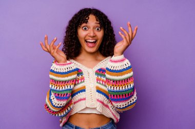 Mor arka planda izole edilmiş genç melez kadın hoş bir sürpriz yaşıyor, heyecanlı ve el kaldırıyor..