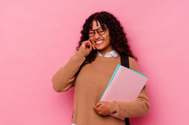 Genç öğrenci melez kadın pembe arka planda izole edilmiş kulakları elleriyle kapatıyor..