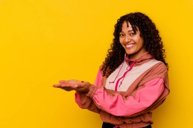 Pembe arka planda izole edilmiş genç melez bir kadın avucunun içinde bir kopya alanı tutuyor..