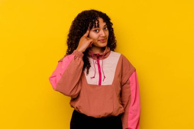 Pembe arka planda izole edilmiş genç melez bir kadın şakağı parmağıyla işaret ediyor, düşünüyor ve bir göreve odaklanıyor..