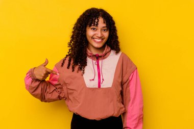 Pembe arka planda izole edilmiş genç bir ırk kadını gömlek fotokopisini elle gösteriyor, gururlu ve kendinden emin.