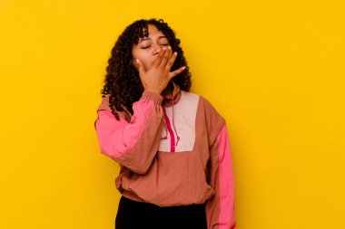 Pembe arka planda soyutlanmış genç melez bir kadın esniyor. Ağzıyla ağzını kapatan yorgun bir hareket sergiliyor..