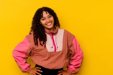 Pembe arka planda izole edilmiş genç melez kadın ellerini kalçasında tutuyor..