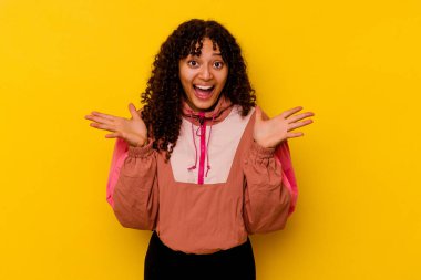 Pembe arka planda izole edilmiş genç melez bir kadın zaferi veya başarıyı kutluyor, şaşırıyor ve şok oluyor..