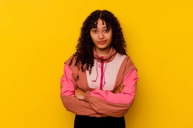 Genç melez kadın pembe arka planda izole edilmiş, mutsuz, iğneleyici bir ifadeyle kameraya bakıyor..