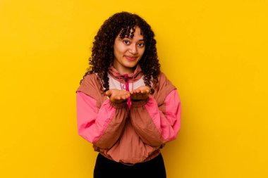 Pembe arka planda izole edilmiş genç bir ırk kadını elinde avuç içi bir şeyle kameraya sunuyor..