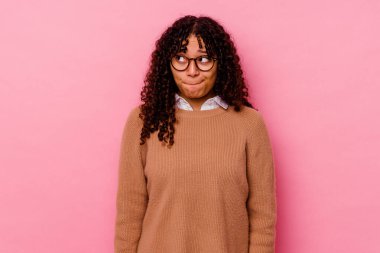Pembe arka planda izole edilmiş genç melez kadın kafası karışmış, kuşkulu ve güvensiz hissediyor..