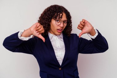 Beyaz arka planda izole edilmiş genç iş kadını başparmağını aşağı gösteriyor ve hoşlanmadığını ifade ediyor..