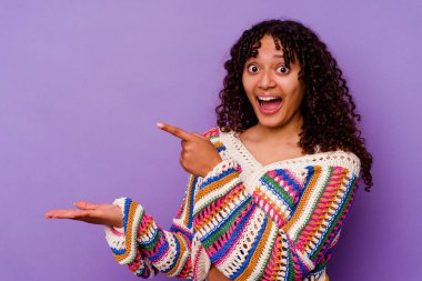 Mor arka planda izole edilmiş genç bir ırk kadını heyecanlı bir şekilde avucunun içinde bir kopyasını tutuyor..