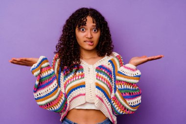 Mor arka planda soyutlanmış genç melez bir kadın. Kopya alanını tutmak için kafası karışık ve omuz silkiyor..