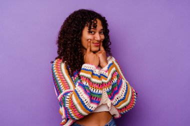 Mor arka planda izole edilmiş genç melez kadın iki seçenek arasında kuşkulanıyor.