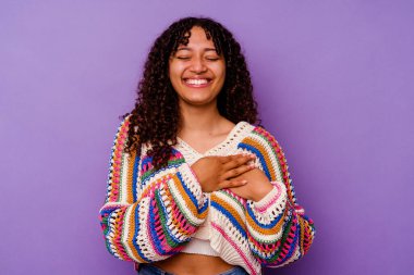 Mor arka planda soyutlanmış genç melez bir kadın. Gülüyor, ellerini kalbe koyuyor, mutluluk kavramını koruyor..