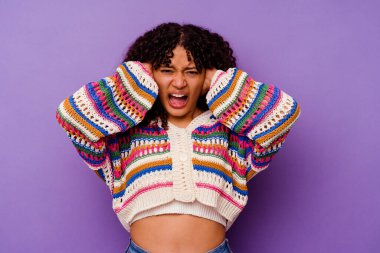 Mor arka planda izole edilmiş genç bir ırk kadını. Kulaklarını ellerle kapatıyor. Çok fazla ses duymamaya çalışıyor..