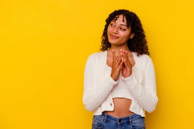 Genç melez kadın sarı arka planda izole edilmiş bir plan yapıyor, bir fikir kuruyor..