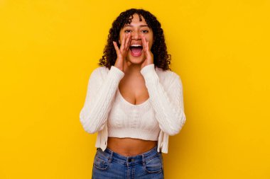 Sarı arka planda izole edilmiş genç bir ırk kadını heyecanlı bir şekilde bağırıyor..