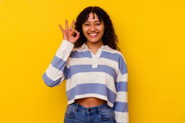 Sarı arka planda izole edilmiş genç melez bir kadın neşeli ve kendinden emin, iyi bir hareket gösteriyor..