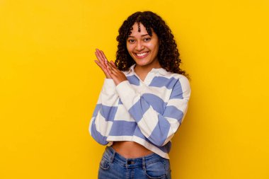 Sarı arka planda soyutlanmış genç melez bir kadın enerjik ve rahat hissediyor, ellerini ovuşturuyor..